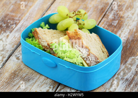 Rustikales Brot-Käse-Sandwiches und grüne Trauben in Lunch-box Stockfoto