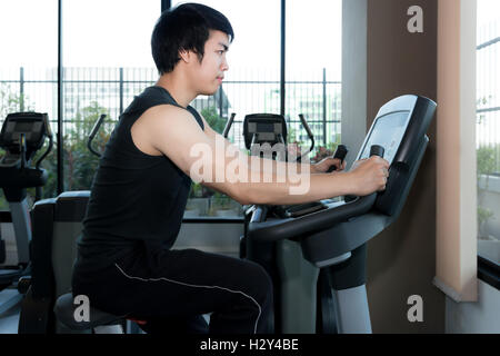 Mann in der Turnhalle. Asiatische junge Mann seine Beine tun Cardio-Training auf Fahrrad im Fitness-Studio trainieren. Stockfoto