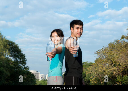 Asiatische junge Mann und Frau Trinkwasser aus Wasserflasche nach Fitness Sport trainieren Sie im Park. Stockfoto