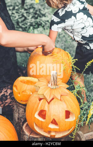Nicht erkennbare Tochter und Mutter zieht Samen und faseriges Material aus einem Kürbis vor dem Schnitzen für Halloween. Bereitet eine Buchse Stockfoto