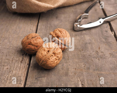 Drei Walnüsse vor einem Jute Beutel gefüllt mit Walnüssen Stockfoto