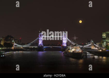Full Moon rising über die beleuchtete Tower Bridge, HMS Belfast Museumsschiff und der Themse, London, UK Stockfoto