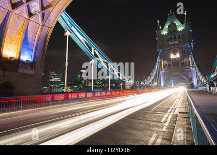 Skyline der City of London und Glanz des Verkehrs auf die Tower Bridge über die Themse bei Nacht, London, UK Stockfoto