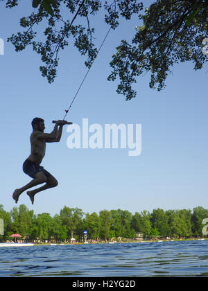 Wien, Wien: junger Mann im Swing über Wasser, Alte Donau (Alte Donau), 22., Wien, Österreich Stockfoto