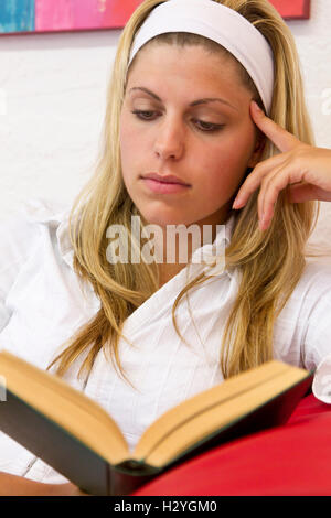 Junge Frau liest ein Buch auf dem sofa Stockfoto