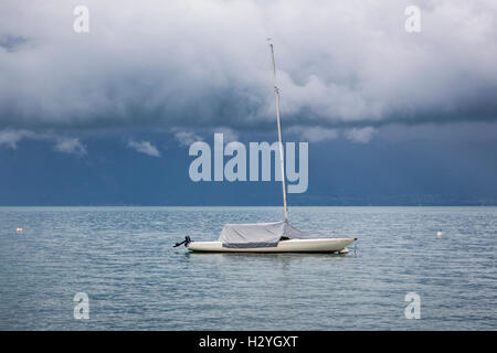 Einsamer Yacht unter niedrigen rollenden Gewitterwolken über dem Genfer See, Schweiz Stockfoto