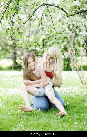 Junge Mutter mit ihrer Tochter in einem Garten Stockfoto