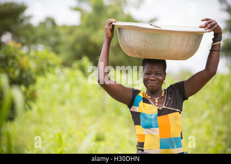 Eine Frau trägt ein Becken auf dem Kopf im ländlichen Réo Abteilung, Burkina Faso, Westafrika. Stockfoto