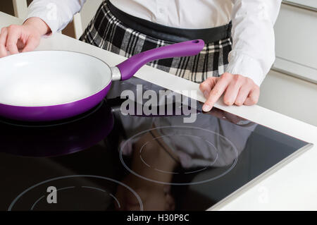 Eine Frau ist Induktions-Kochfeld einschalten. Stockfoto