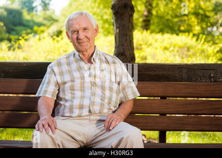 Alter Mann sitzt auf der Bank. Stockfoto