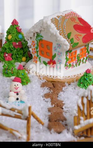 Lebkuchenhaus gemalt im Ethno-Stil unter den Bäumen und Schnee Stockfoto