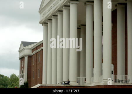 Student am Laptop an den großen Säulen am Eingang in der DeMoss Hall der Liberty University in Lynchburg, Virginia, USA Stockfoto