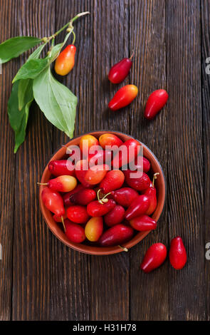 Cornelian Cherry Berry in Schüssel auf hölzernen Hintergrund Stockfoto