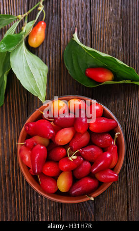 Cornelian Cherry Berry in Schüssel auf hölzernen Hintergrund Stockfoto