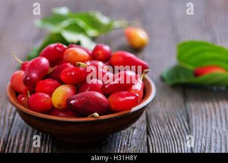 Cornelian Cherry Berry in Schüssel auf hölzernen Hintergrund Stockfoto