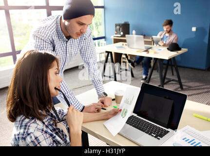 Coworking-Prozess, Designer-Team arbeitet modernes Büro. Foto junge kreative Manager zeigt neue Startup Idee Monitor. Desktop-Computer auf Holztisch. Der Hintergrund jedoch unscharf, Film-Effekt. Stockfoto