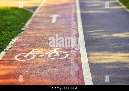 Roten Radweg auf Bürgersteig mit gemalten weißen Pfeil und Fahrrad schildern. Textfreiraum Stockfoto