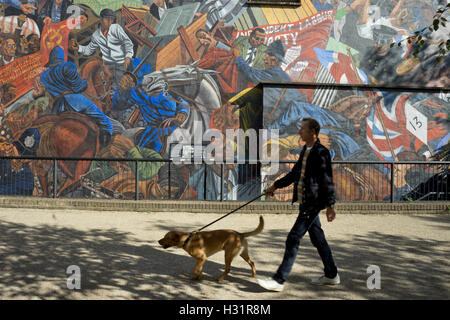 Mann geht Hund vorbei an der Schlacht der Kabel St.-Wandbild von Kabel St. in East London, UK, zum 80. Jahrestag des Ereignisses am 4. Oktober 1936 Stockfoto