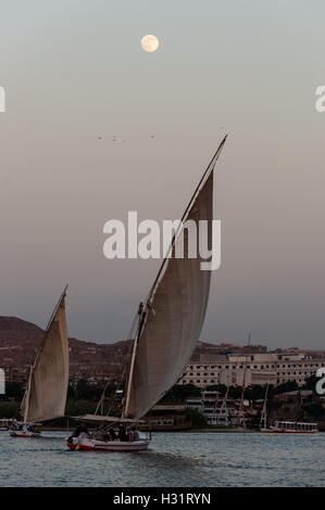 Ägypten. Assuan steht am Ostufer des Nils. Eine Feluke ist einem traditionellen Segelboot aus Holz, mit dem Mond als Hintergrund. Stockfoto
