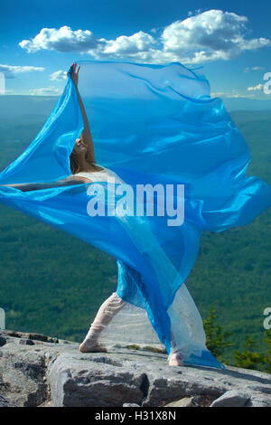 Tänzerin im weißen Kleid tanzen mit blauem Stoff im Wind am Gipfel des Mt. Kearsarge, New Hampshire. Stockfoto