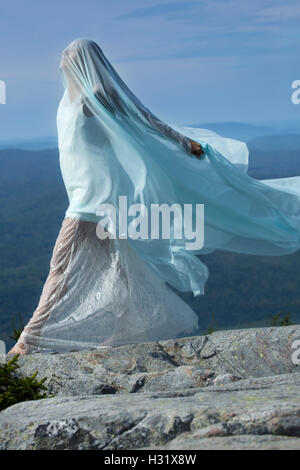 Tänzerin in weißes Kleid gehüllt in grünem Stoff im Wind am Gipfel des Mt. Kearsarge, New Hampshire. Stockfoto