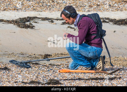 Mann auf der Suche nach einem Schatz mit einem Metalldetektor am Strand. Stockfoto