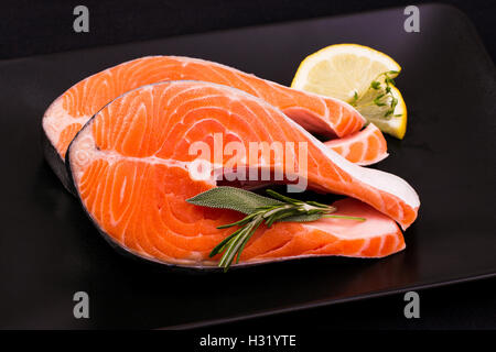 Zwei köstliche rohen Lachs in Scheiben schneiden mit Gewürzen auf schwarzem Teller Stockfoto