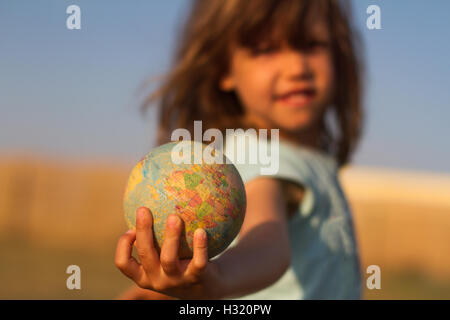 Vorderansicht des eine Kinderhand hält ein beschädigtes Spielzeug Globus, geringe Schärfentiefe Stockfoto