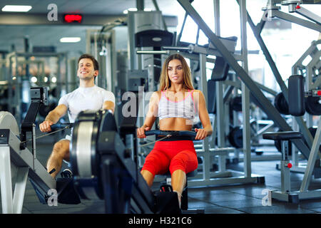 Sportliche paar - Mann und Frau, die Schulung an Zeile Maschine im Fitness-Studio Stockfoto