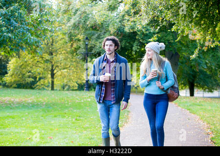 Junges Paar genießen Sie einen Spaziergang durch den Park. Sie sind sowohl Kaffee trinken und reden. Stockfoto