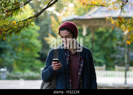 Junger Mann mit einem Smartphone. Er ist in einem Outdoor-Park. Stockfoto