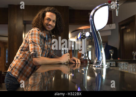 Junger Mann in einer Bar mit einem Pint, Lächeln für die Kamera. Stockfoto