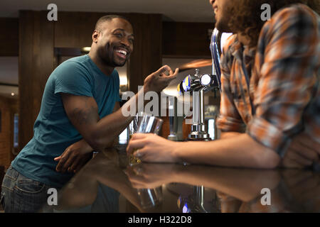 Junge Mann stand an der Bar im Gespräch mit der Barkeeper Stockfoto