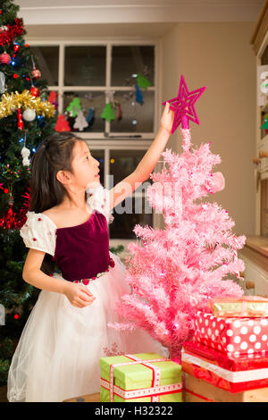 Chinesin, einen Stern auf ihrem eigenen Baum zu Weihnachten. Stockfoto