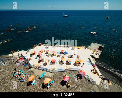 Menschen genießen das sommerliche Wetter auf einer künstlich angelegten Strand Plattform Funchal auf der portugiesischen Insel Madeira. Stockfoto