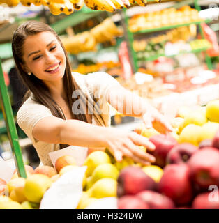 Hübsche junge Frau, die Äpfel auf dem Markt zu kaufen Stockfoto