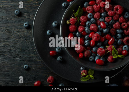 schwarze Platte mit gesunden Beeren auf einem dunklen Hintergrund Stockfoto