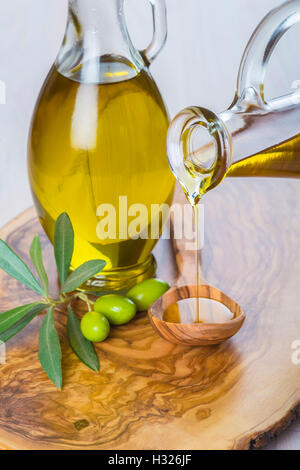 Flasche natives Olivenöl extra auf einem hölzernen Löffel Gießen Stockfoto