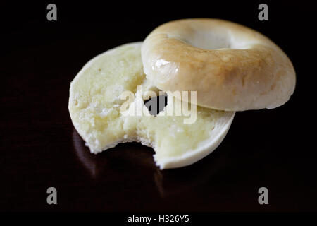 Ein heiße Bagel in zwei Hälften geschnitten und mit Butter. Ein Biss wurde aus der Butter Bagel übernommen Stockfoto