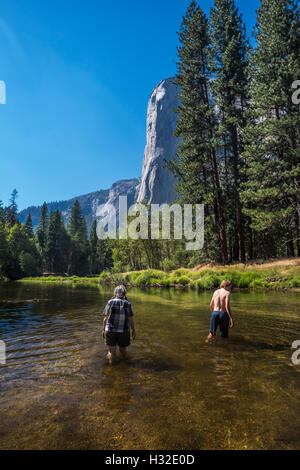 Karen und Max Rentz waten im Merced River in der Nähe von El Capitan im Yosemite Valley, Yosemite-Nationalpark, Kalifornien, USA Stockfoto