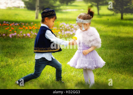 kasachische kleine Jungen und Mädchen gemeinsam spielen im Sommerpark Stockfoto