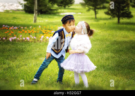 kasachische kleine Jungen und Mädchen gemeinsam spielen im Sommerpark Stockfoto