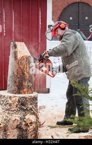 Hamina, Finnland - 13. Dezember 2014: Finnische Bildhauermeister mit einer Kettensäge produziert Holzskulptur Stockfoto