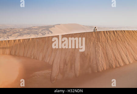 Mann in traditioneller Kleidung in einer Wüste bei Sonnenaufgang Stockfoto