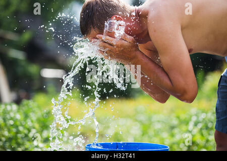 Mann aktualisiert sich selbst mit einem Schuss von kühle, frische Wasser auf seinem Gesicht. Stockfoto