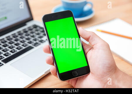 Mann Hand hält Smartphone mit leeren Bildschirm auf Holztisch Stockfoto