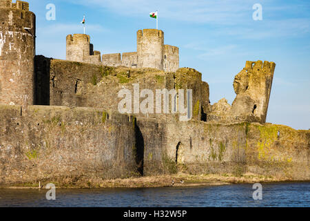 Wassergraben, der Wände und der schiefe Turm von Caerphilly Castle im niedrigen Abendlicht, Caerphilly, Wales, UK Stockfoto