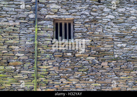 Ein sehr alter Stein Bauernhof Gebäude mit zerbrochenen Fenstern und Türen aus Holz. Stockfoto