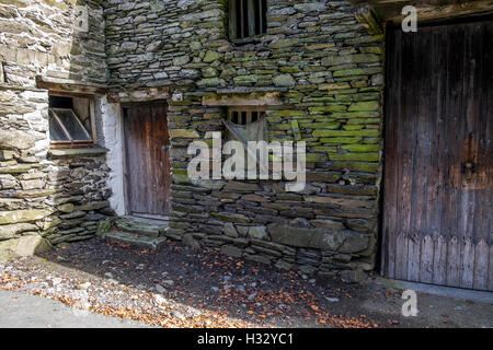 Ein sehr alter Stein Bauernhof Gebäude mit zerbrochenen Fenstern und Türen aus Holz. Stockfoto