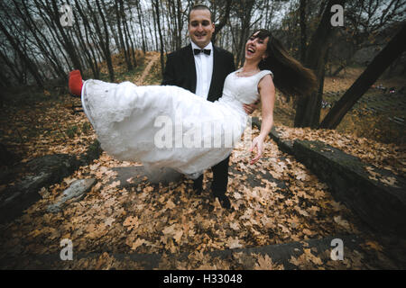 Bräutigam hält Braut im Arm Stockfoto
